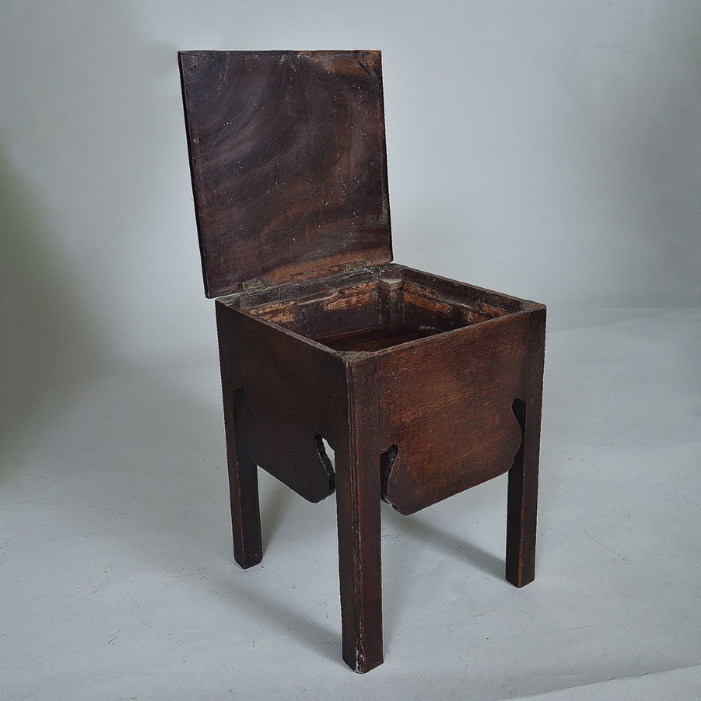 An early nineteenth-century dark mahogany box stool featuring a flat top lid, square legs, and decorative shaped aprons. View III