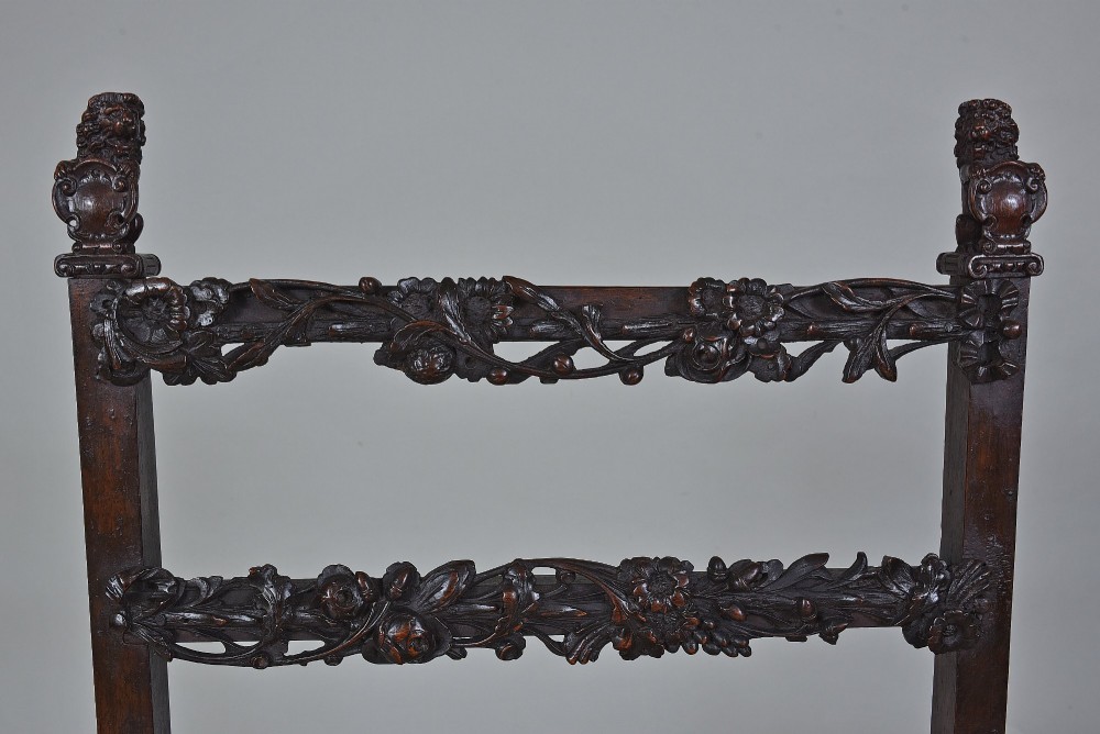 An 18th-century Italian dark walnut armchair featuring intricate openwork foliage carving across the back rails and front stretcher, turned supports, and a patterned woven seat. View VI