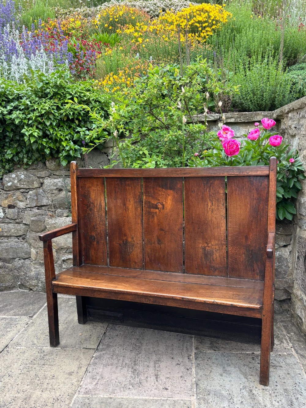 An 18th-century oak settle with a high panelled backrest, flat armrests, and straight legs. View II