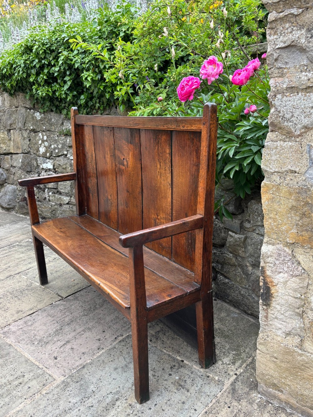 An 18th-century oak settle with a high panelled backrest, flat armrests, and straight legs. View III