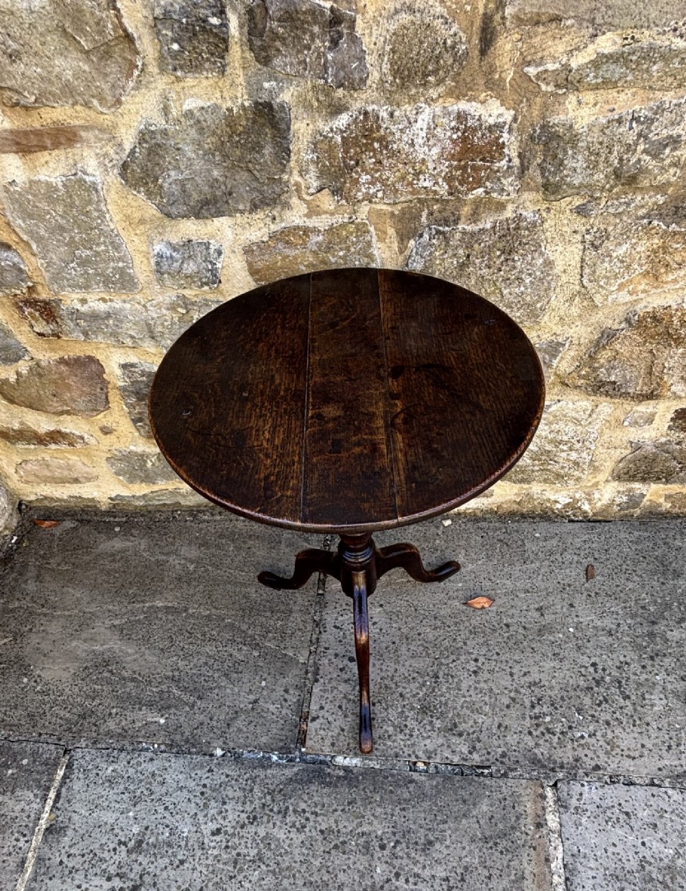 An 18th-century dark oak tripod table featuring a circular top, turned central pedestal stem, and three splayed legs. View II