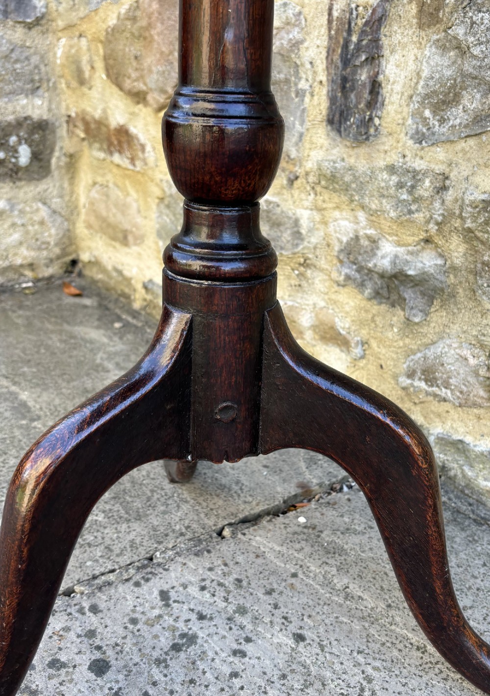 An 18th-century dark oak tripod table featuring a circular top, turned central pedestal stem, and three splayed legs. View III