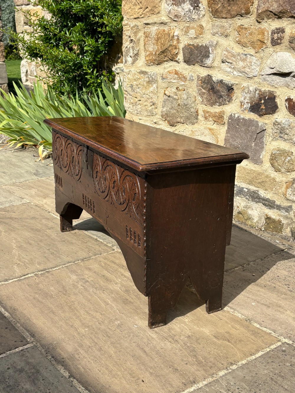 A 17th-century carved oak coffer featuring relief lunette carvings, an iron lockplate, and a dark polished timber finish. View II