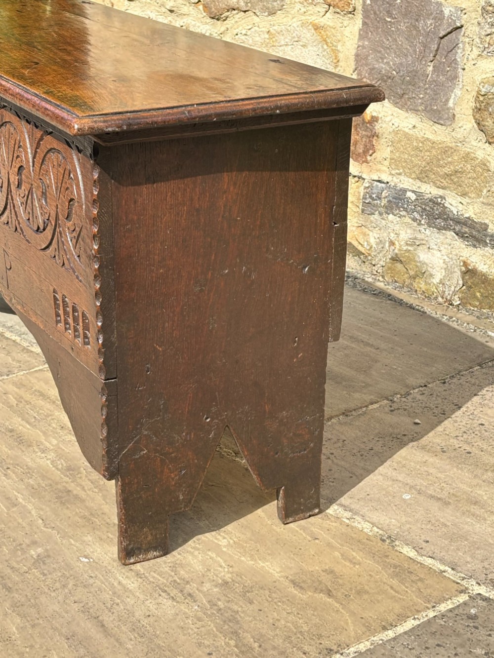A 17th-century carved oak coffer featuring relief lunette carvings, an iron lockplate, and a dark polished timber finish. View III