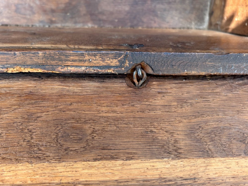 A 17th-century carved oak coffer featuring relief lunette carvings, an iron lockplate, and a dark polished timber finish. View V