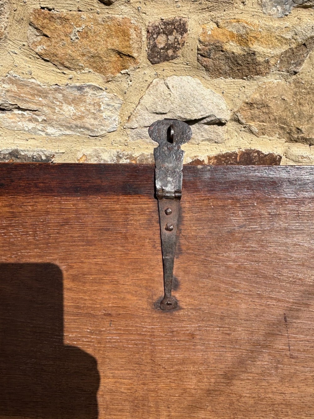 A 17th-century carved oak coffer featuring relief lunette carvings, an iron lockplate, and a dark polished timber finish. View VI