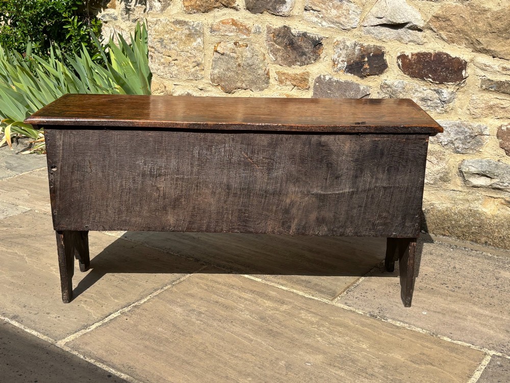 A 17th-century carved oak coffer featuring relief lunette carvings, an iron lockplate, and a dark polished timber finish. View VII