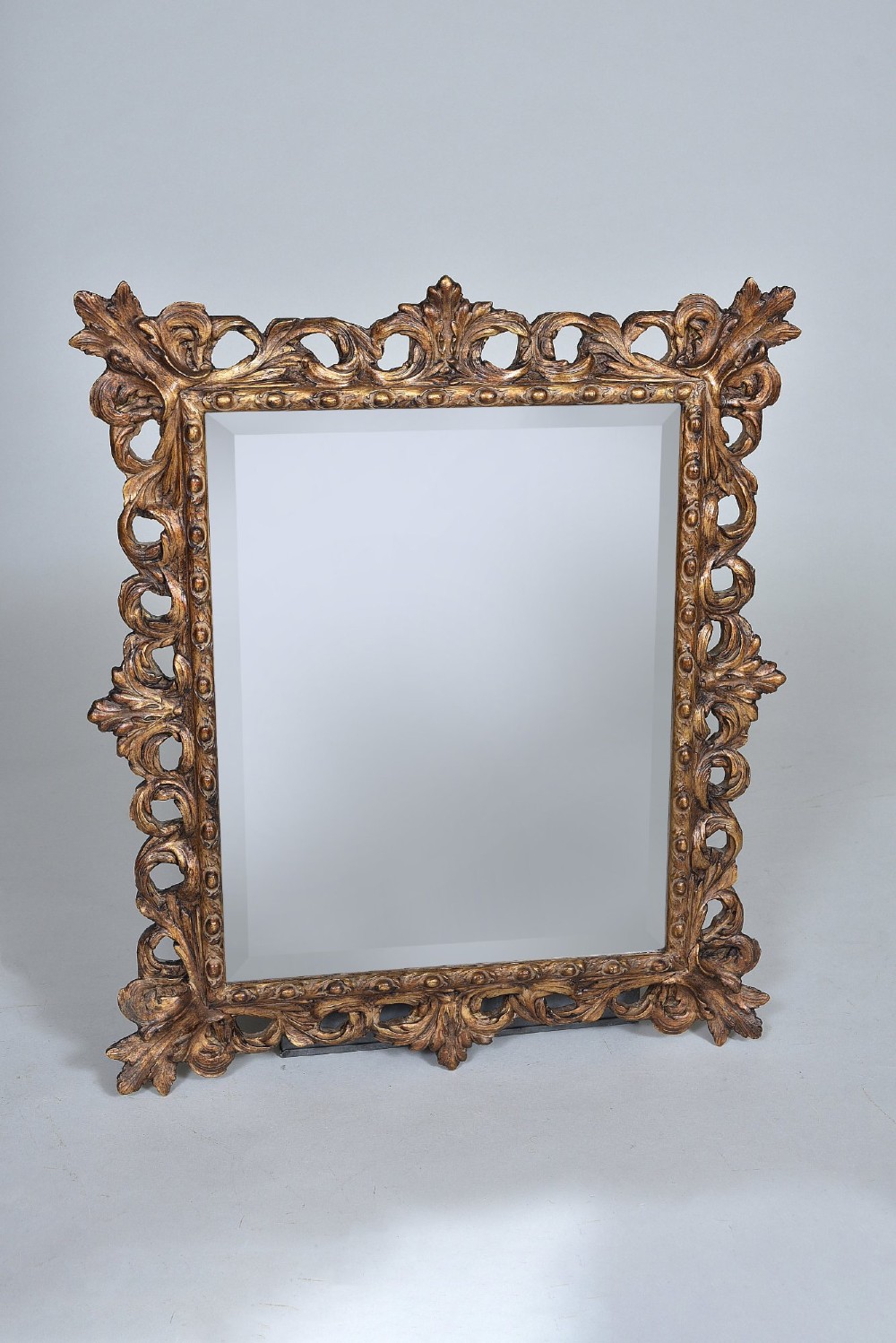 A rectangular nineteenth-century mirror featuring an ornate pierced giltwood frame decorated with carved acanthus leaves and scrollwork.