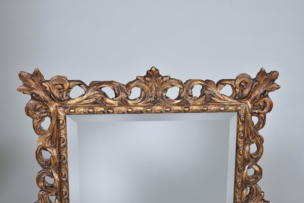 A rectangular nineteenth-century mirror featuring an ornate pierced giltwood frame decorated with carved acanthus leaves and scrollwork. View II
