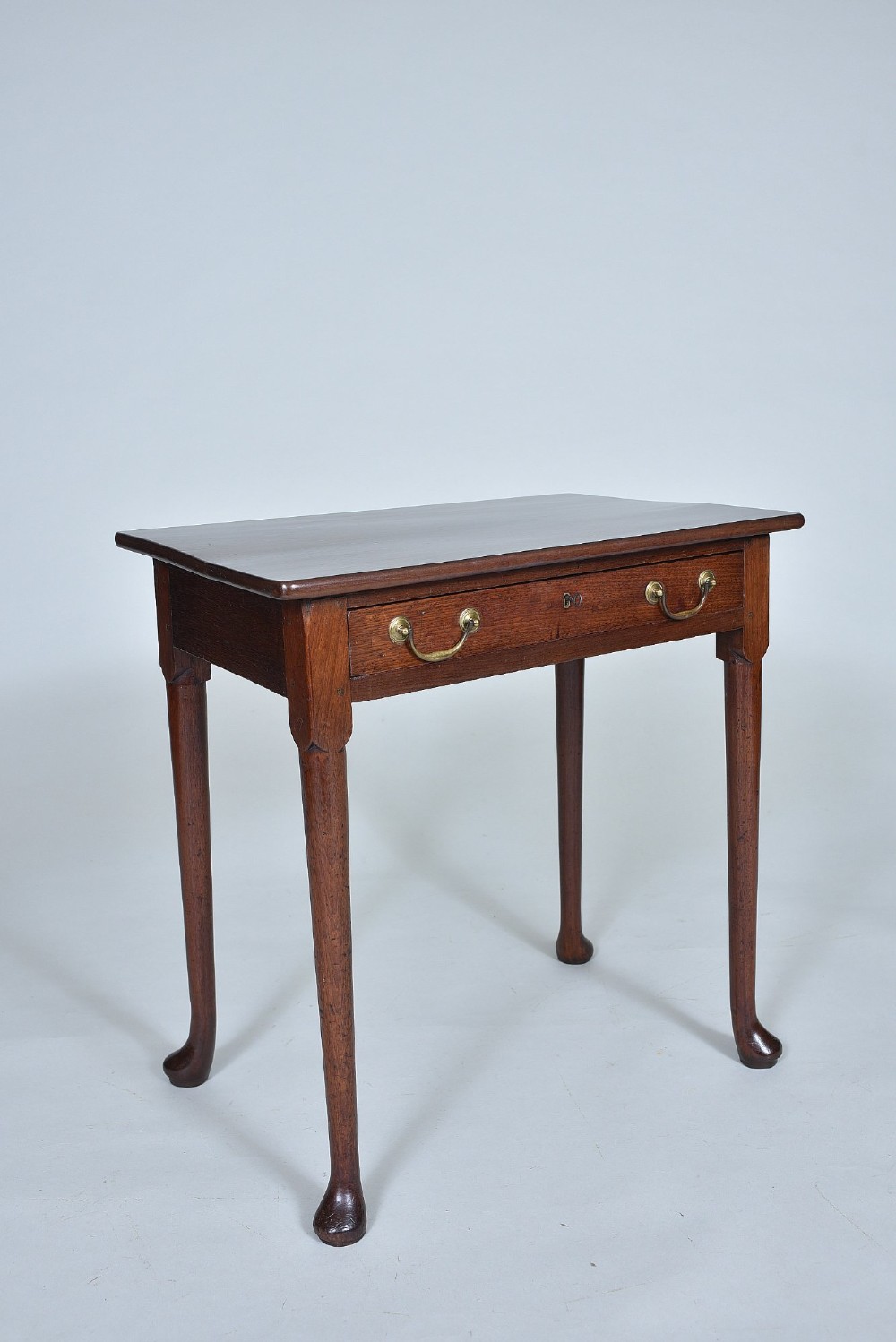 A dark Georgian mahogany side table with a single frieze drawer, brass swan-neck handles, and slender legs ending in pad feet.
