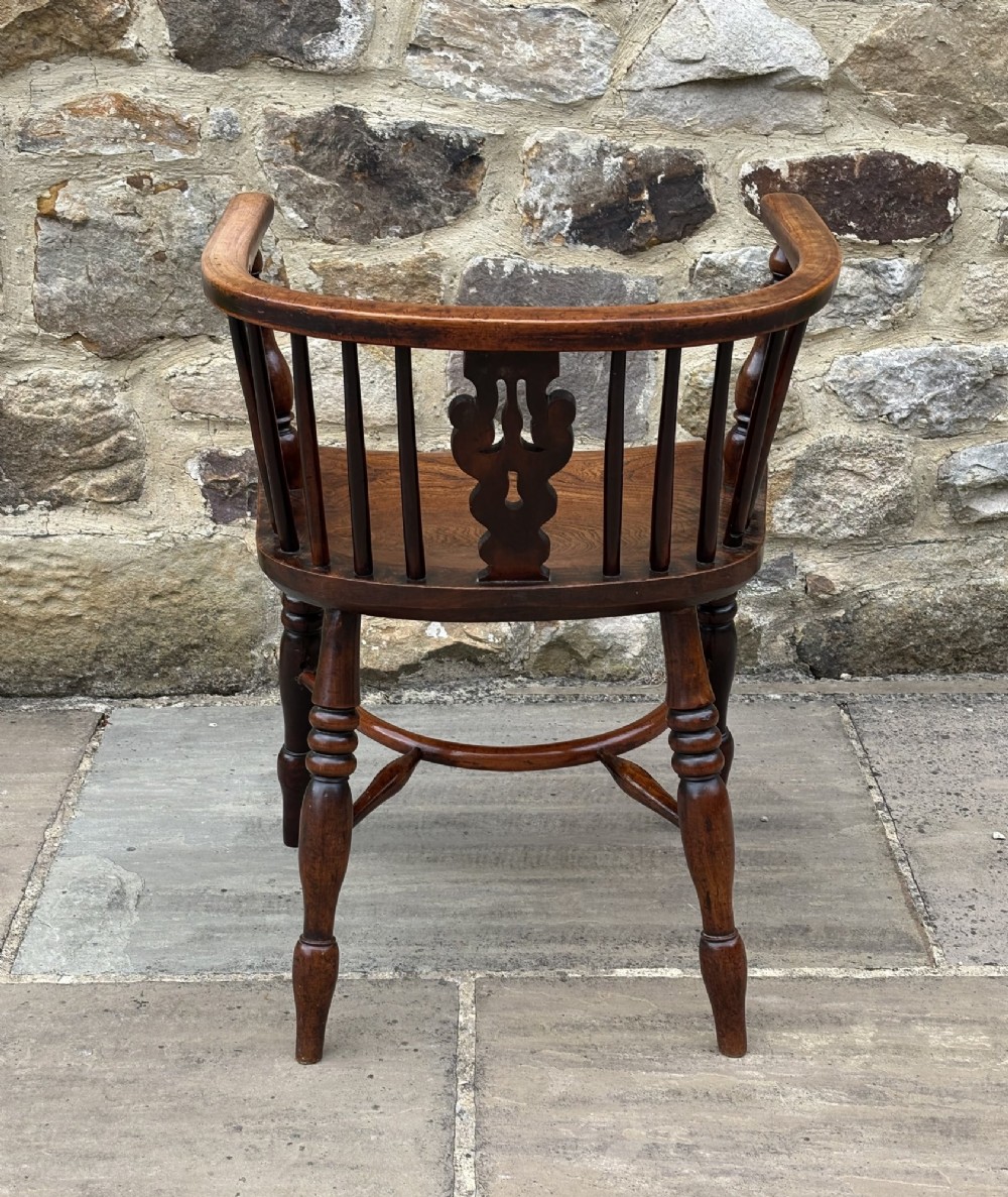 A 19th-century yew wood Windsor armchair featuring a low back rail, turned legs, a shaped seat, and a central pierced back splat flanked by round spindles. View IV