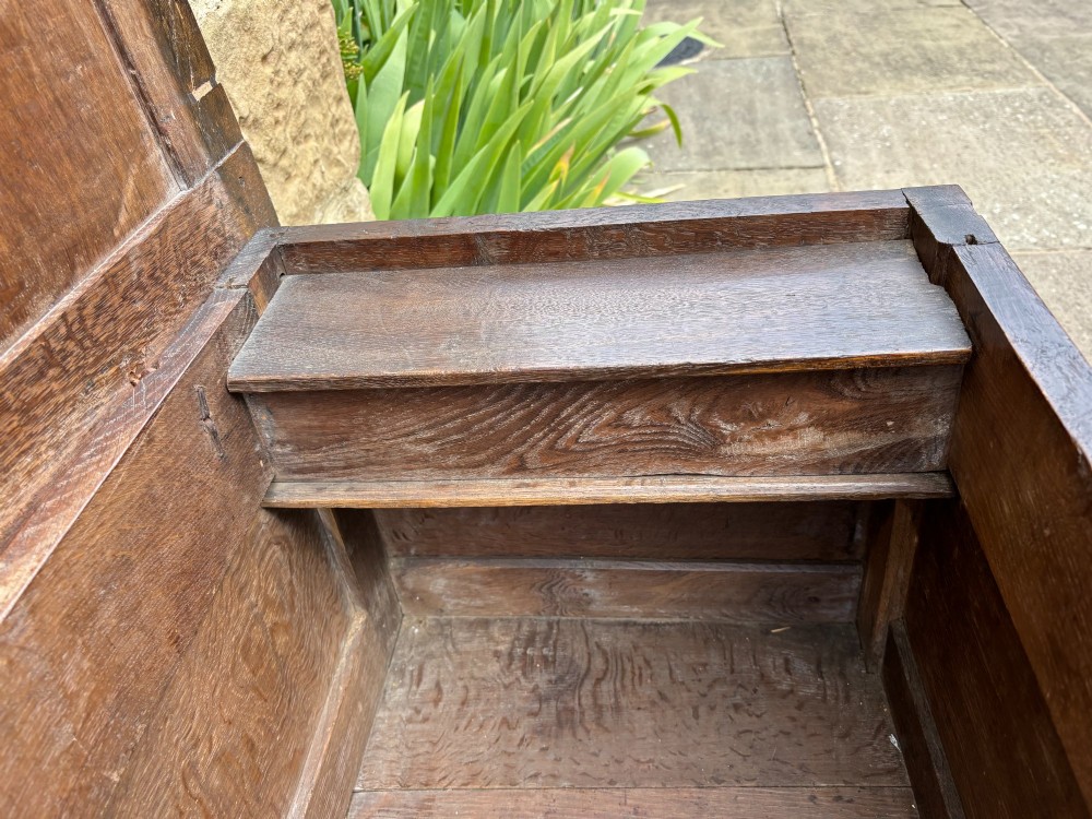 A 17th-century carved oak coffer featuring two carved floral front panels, a carved top frieze, and an iron lockplate. View V