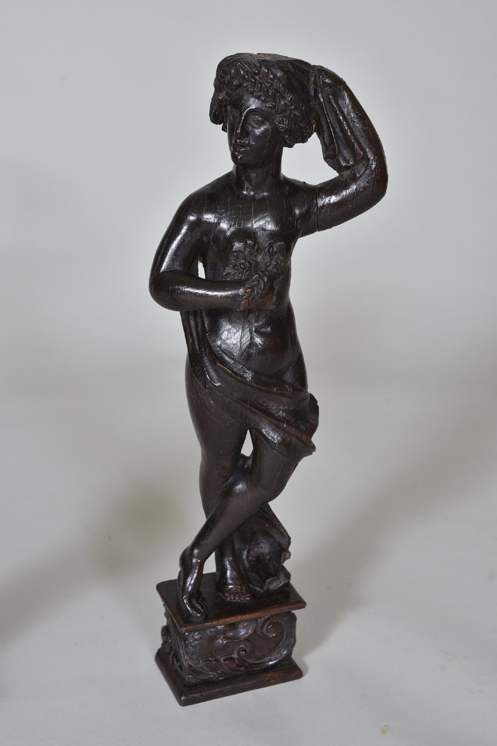 A pair of dark carved oak figures depicting classical drapery-clad subjects standing on carved square pedestals. View IV