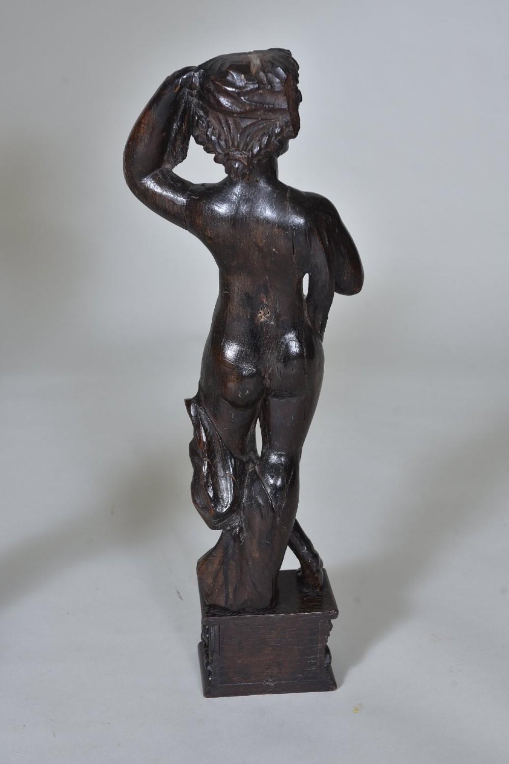 A pair of dark carved oak figures depicting classical drapery-clad subjects standing on carved square pedestals. View VIII