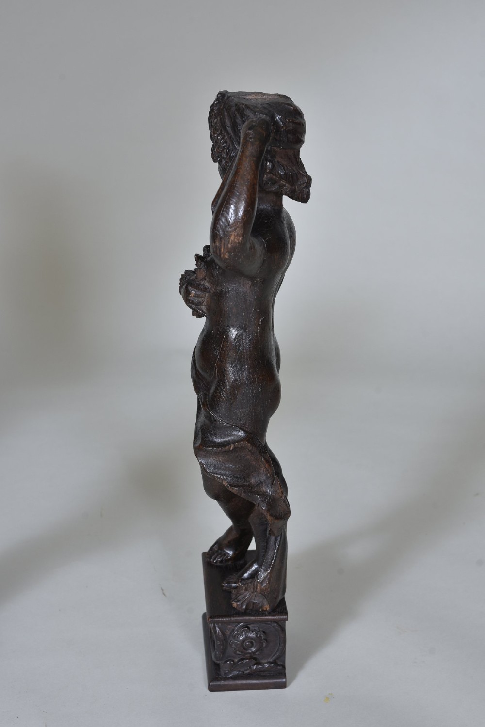 A pair of dark carved oak figures depicting classical drapery-clad subjects standing on carved square pedestals. View IX