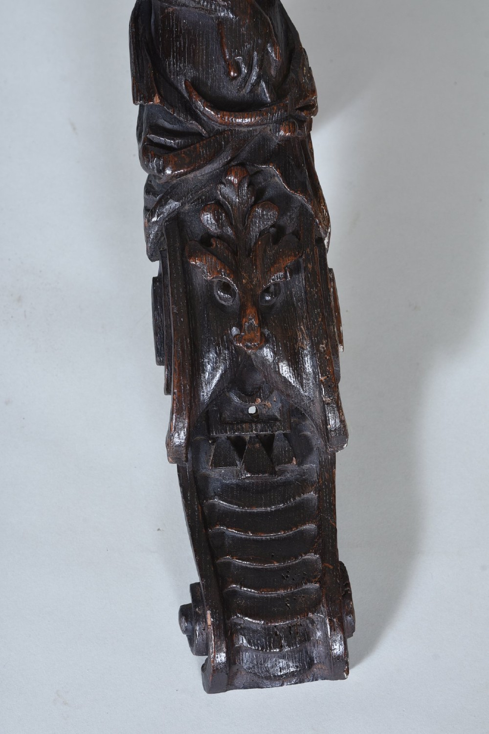 A dark oak 17th-century vertical wood carving featuring a female figure positioned above a carved grotesque mask. View III