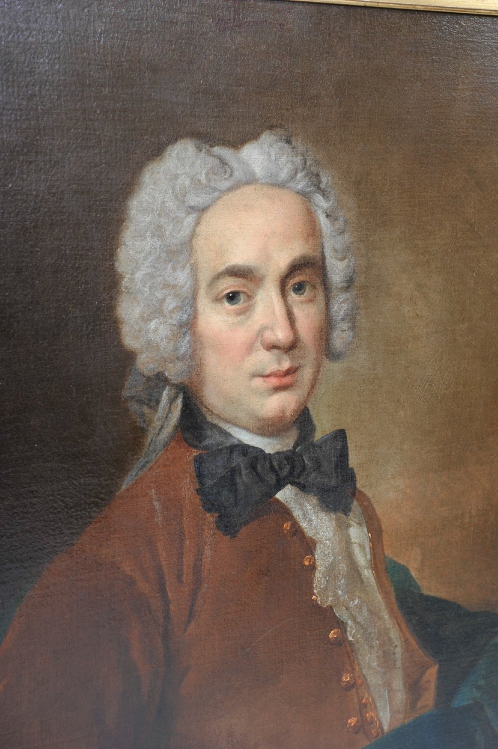 An eighteenth-century oil painting depicting a gentleman wearing a powdered wig, brown coat, black cravat, and blue drape, set within a carved gilt and dark wood frame. View III