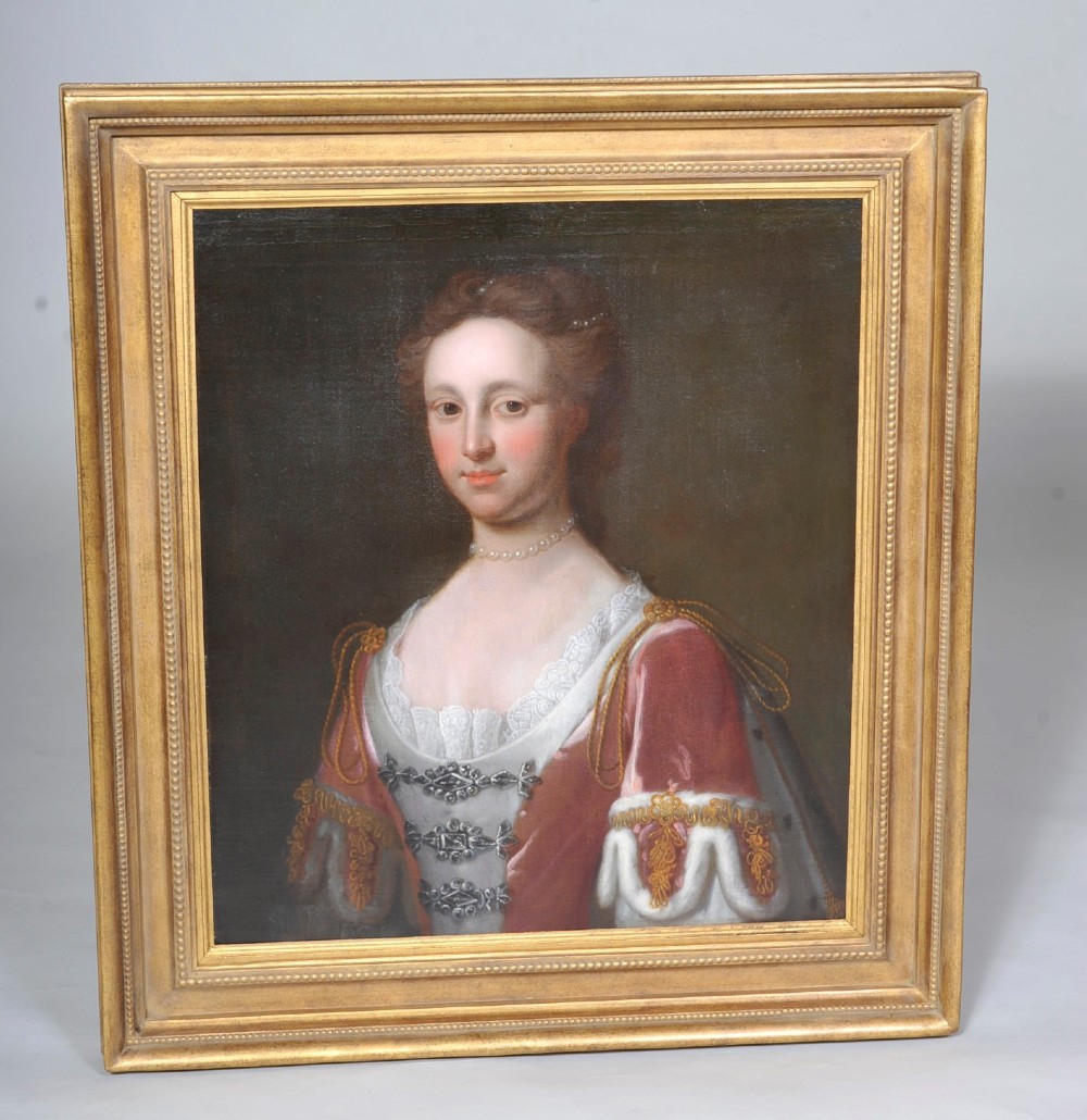 An 18th-century oil portrait of a woman wearing a pearl necklace and lace-trimmed gown, set within a molded gold gilt frame.