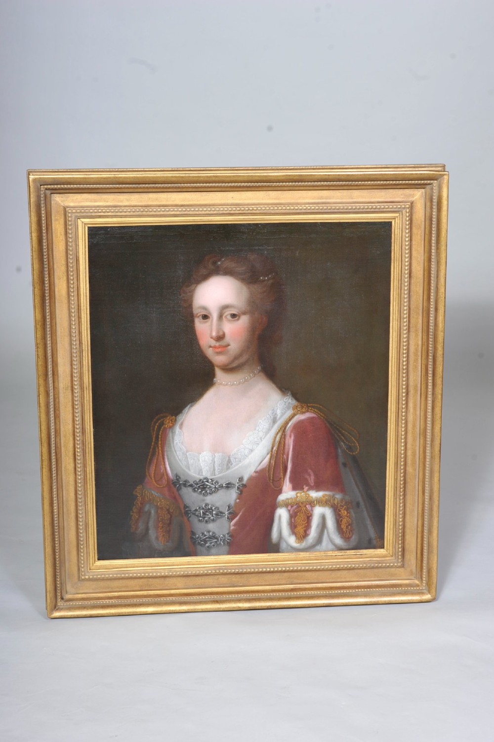 An 18th-century oil portrait of a woman wearing a pearl necklace and lace-trimmed gown, set within a molded gold gilt frame. View II