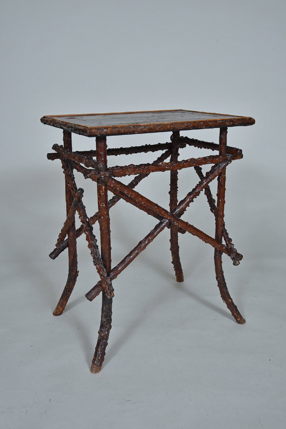 A small rectangular side table constructed from dark brown natural twigs and branches with a smooth lacquered top surface.