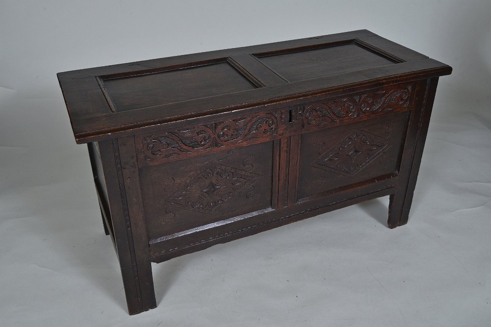 A dark 17th-century oak coffer featuring carved foliate friezes, panelled front with lozenge motifs, and a hinged lid. View II