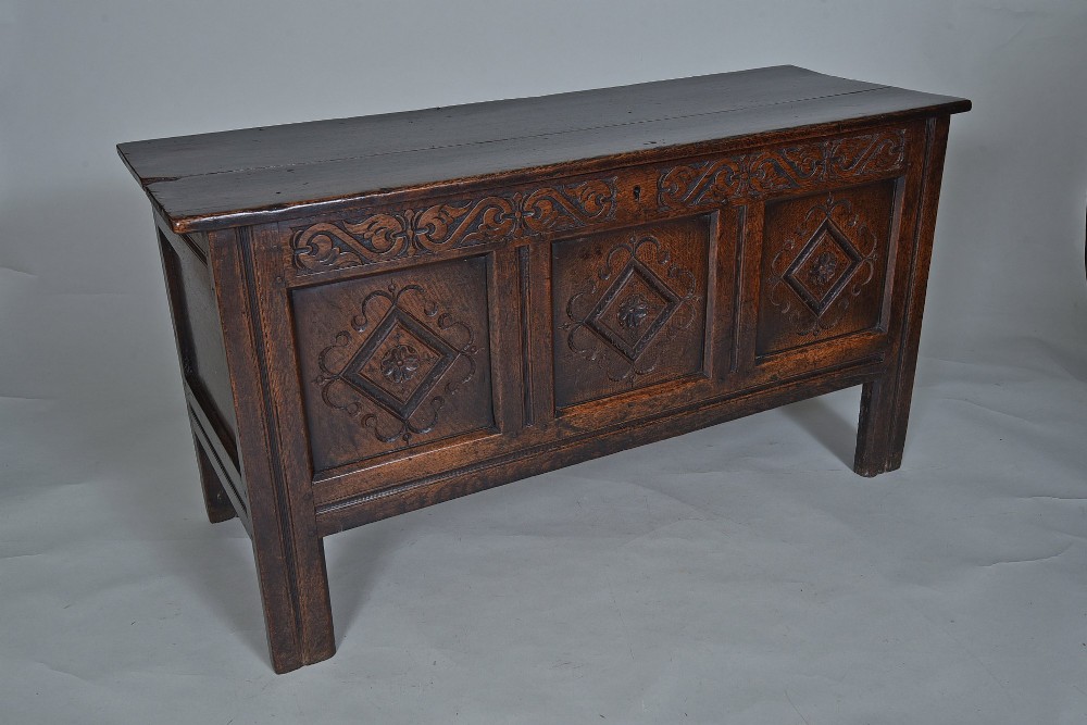 A dark oak seventeenth-century coffer featuring three carved diamond front panels and a carved upper frieze rail.