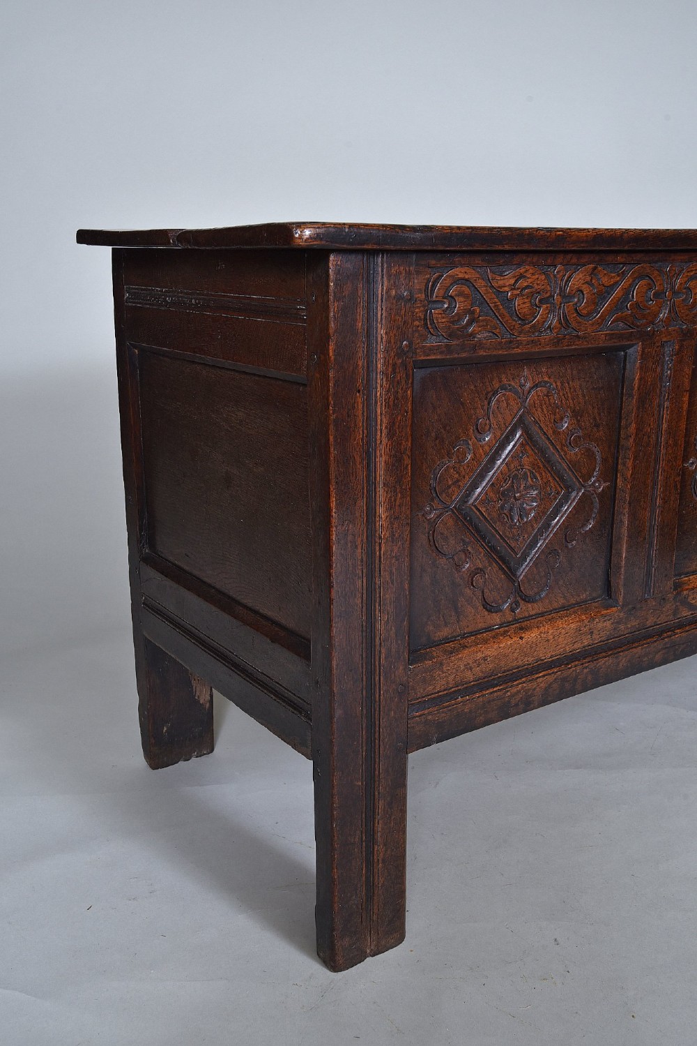 A dark oak seventeenth-century coffer featuring three carved diamond front panels and a carved upper frieze rail. View V