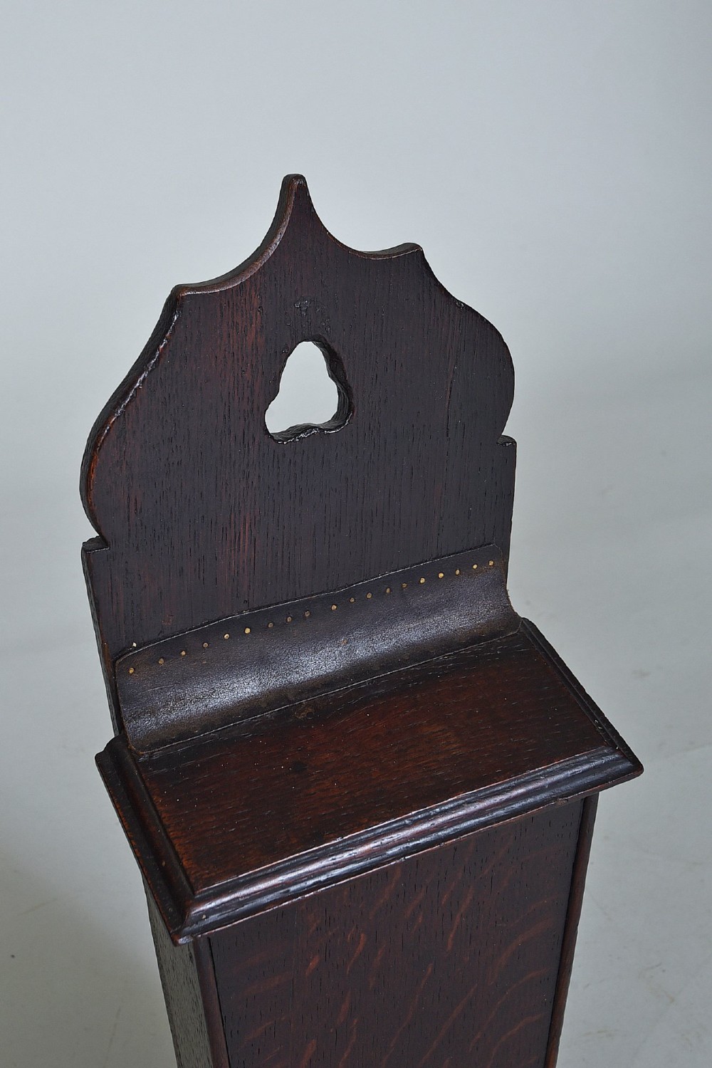 A dark oak wall-hanging candle box featuring a shaped backboard with a hanging aperture, a sliding front cover, and a tapered body. View II
