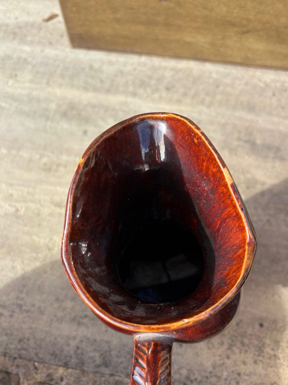 A nineteenth-century ceramic Toby jug depicting a seated man wearing a tricorne hat, finished in a rich, mottled treacle-brown glaze. View IX