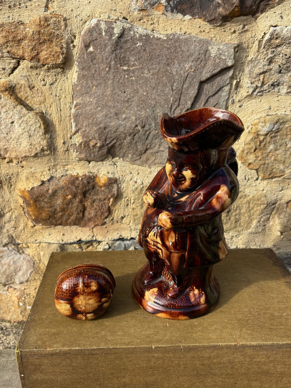 A nineteenth-century ceramic Toby jug depicting a seated man wearing a tricorne hat, finished in a rich, mottled treacle-brown glaze. View X