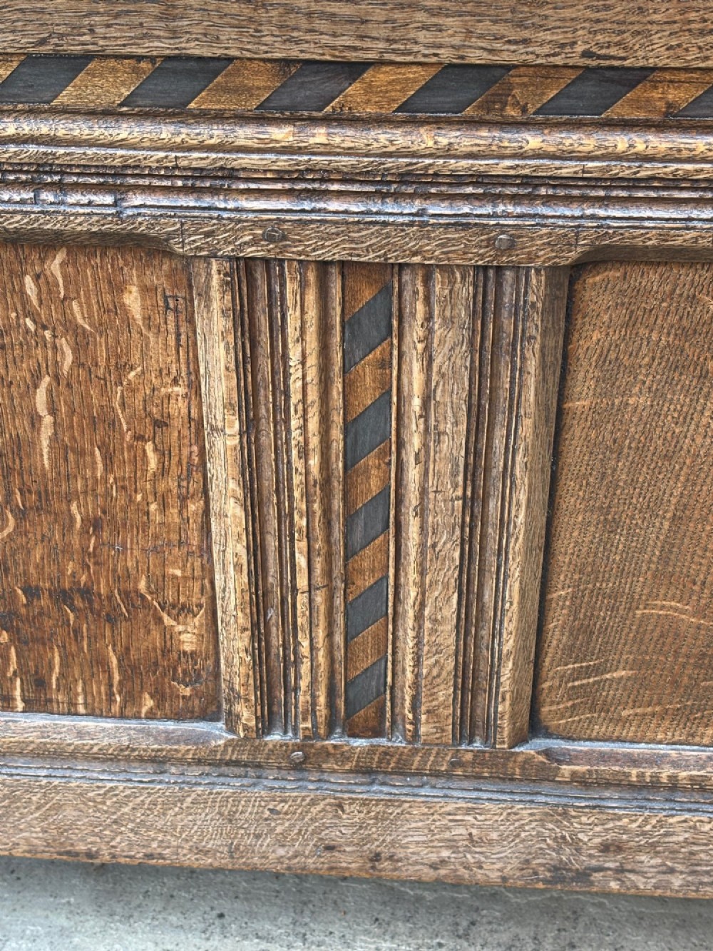 A 17th-century oak coffer featuring a hinged lid, panelled front, and geometric marquetry inlay. View II