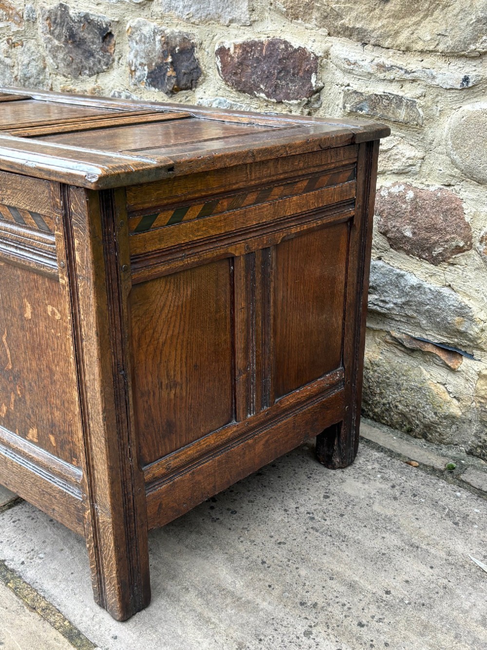 A 17th-century oak coffer featuring a hinged lid, panelled front, and geometric marquetry inlay. View IV