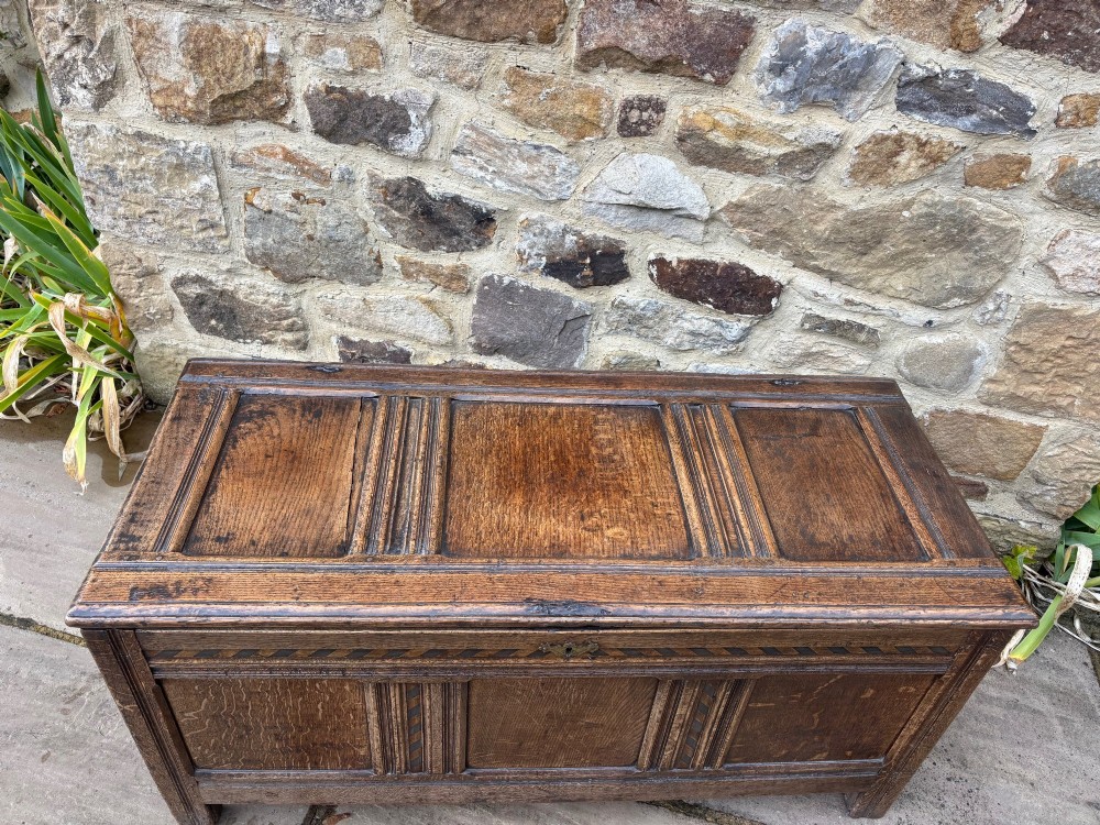 A 17th-century oak coffer featuring a hinged lid, panelled front, and geometric marquetry inlay. View XI