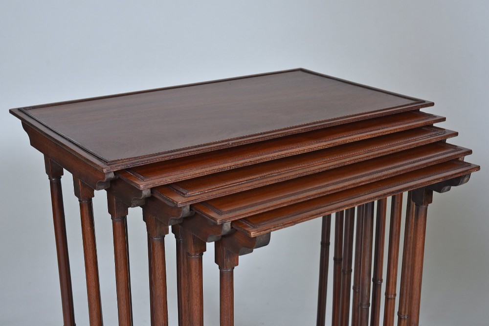 A set of five graduating antique mahogany nesting tables stacked together featuring slender turned legs and trestle feet. View II