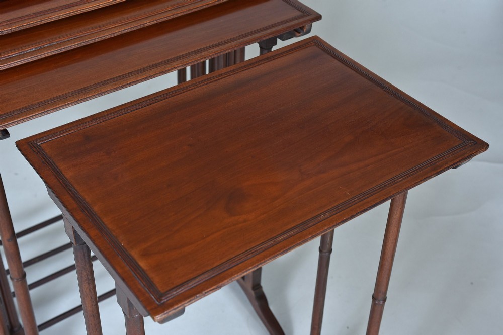 A set of five graduating antique mahogany nesting tables stacked together featuring slender turned legs and trestle feet. View III