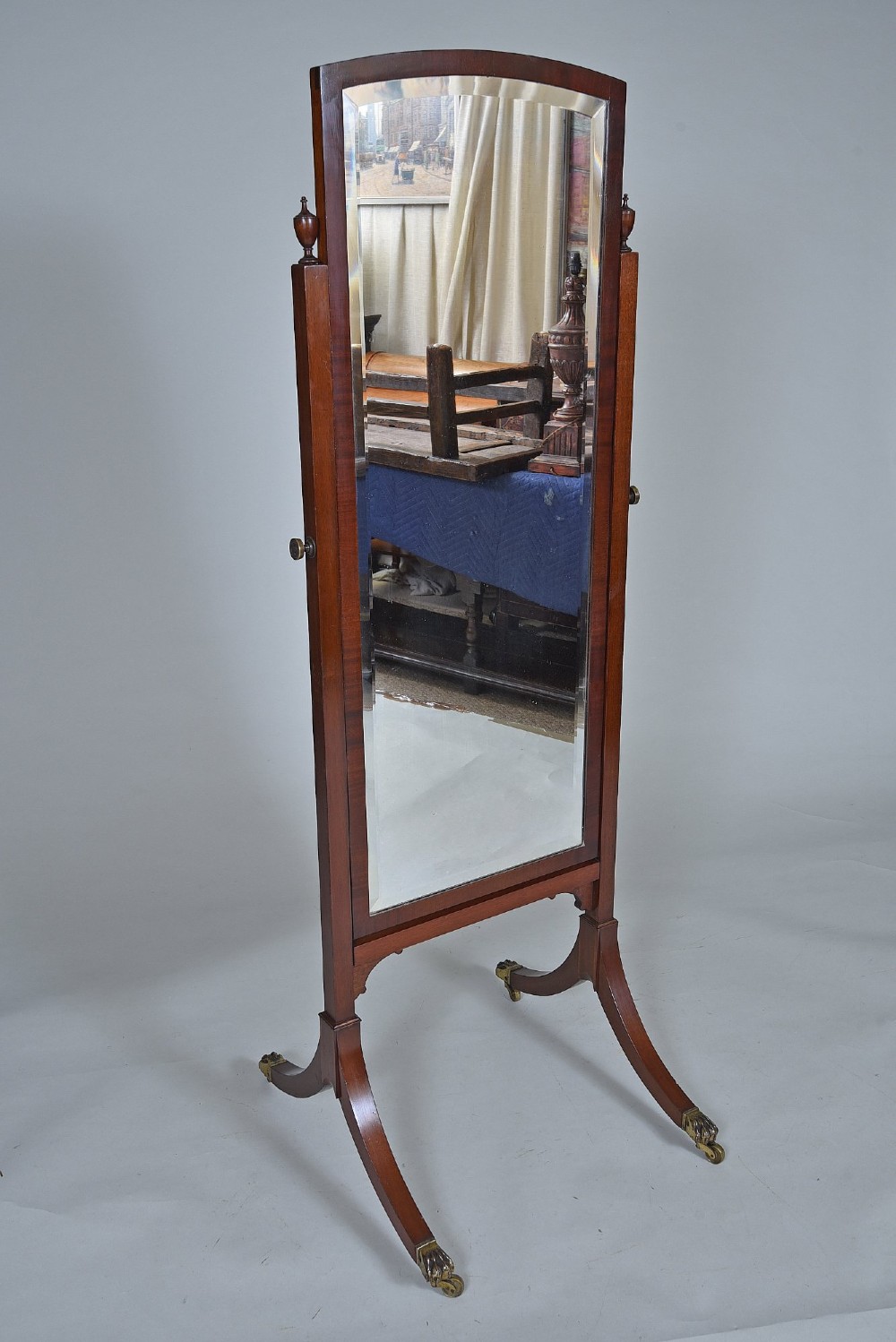 An Edwardian mahogany cheval mirror with an arched frame suspended on upright posts, raised on splayed legs with brass paw castors. View III