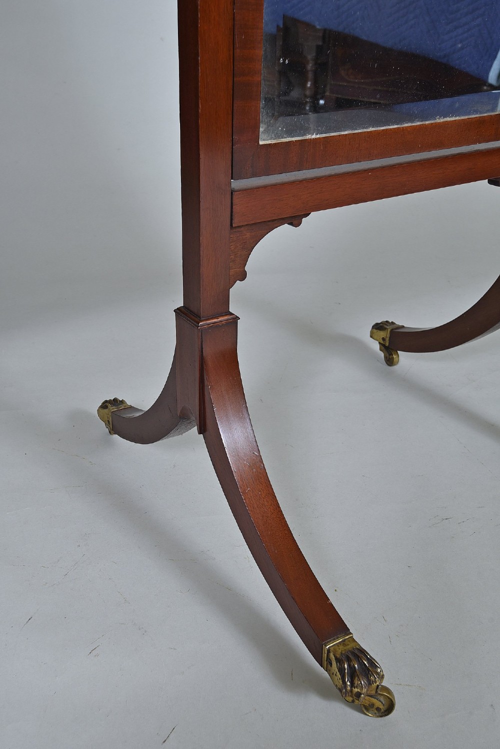 An Edwardian mahogany cheval mirror with an arched frame suspended on upright posts, raised on splayed legs with brass paw castors. View IV