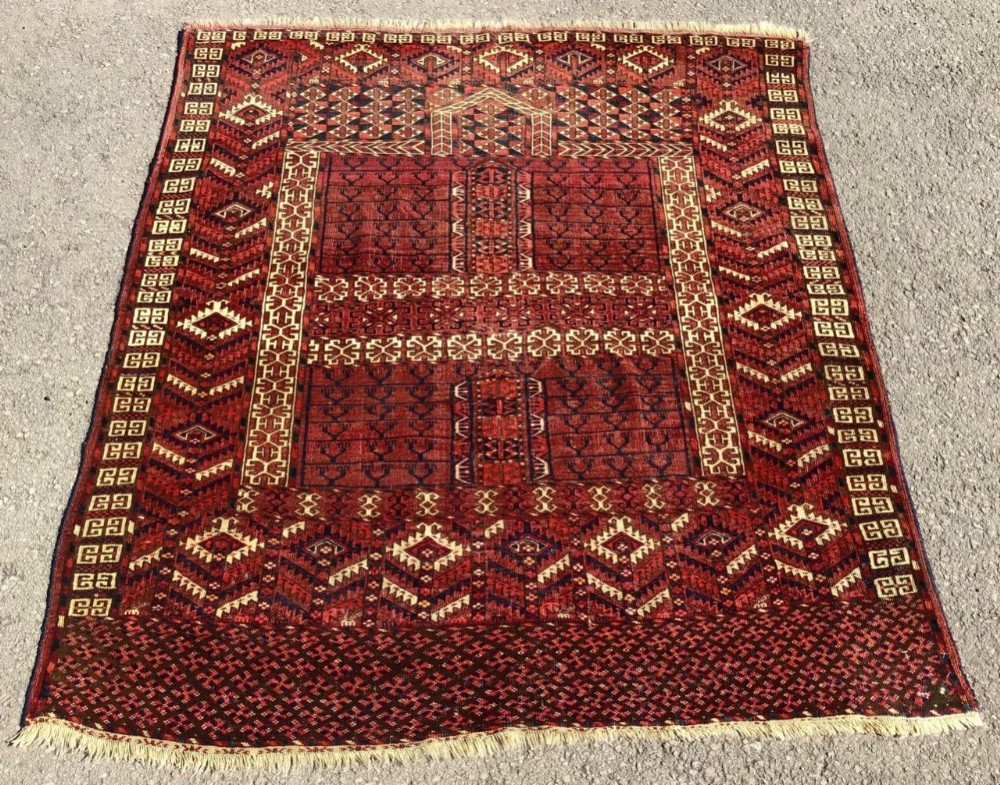 A 19th-century Tekke Turkmen Ensi rug featuring a central four-panel hatchli pattern in terracotta red, dark navy, and ivory geometric motifs framed by decorative borders.