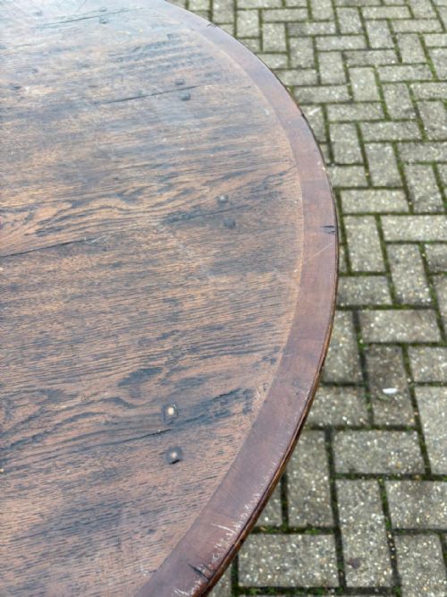 fig 1. An antique dark oak cricket table featuring a circular plank top, three splayed legs, and a lower triangular shelf.