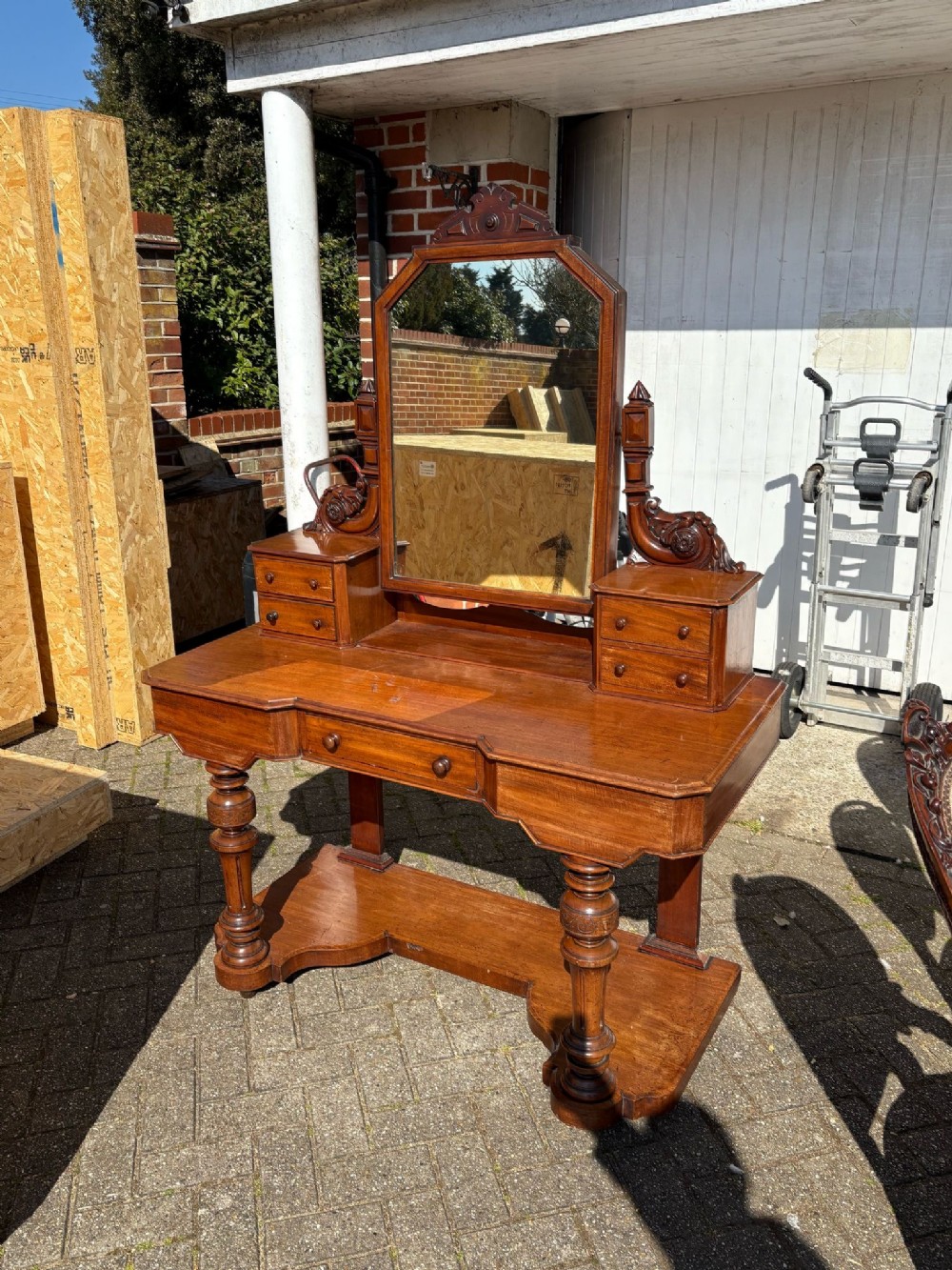 A Victorian mahogany dressing table featuring a central swinging mirror, raised trinket drawers, turned front legs, and a shaped lower shelf.