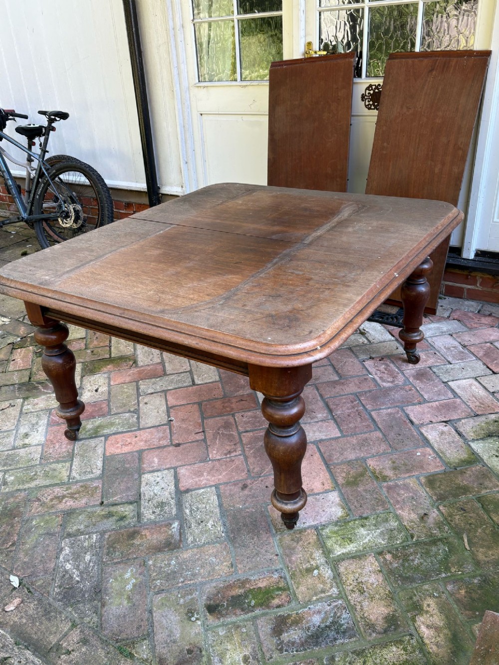A Victorian mahogany extending dining table with heavy turned legs on castors, featuring separate leaf inserts displayed behind.