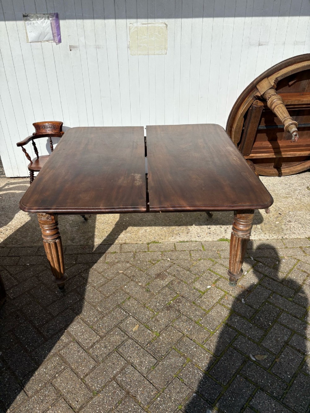 A rectangular dark brown mahogany extending dining table featuring a split top and four turned reeded legs fitted with brass castors.