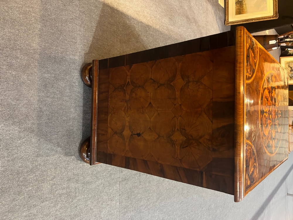 A walnut chest of drawers featuring intricate floral marquetry inlay across the drawer fronts and top surface, fitted with brass drop handles and raised on bun feet. View IV
