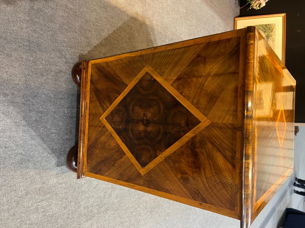 An antique burr walnut chest of drawers featuring inlaid geometric patterns on top, two short over three long drawers with brass handles, and bun feet. View III