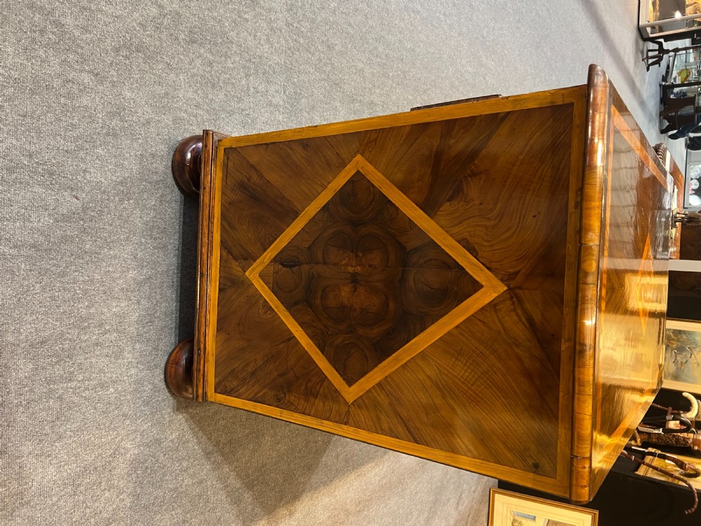An antique burr walnut chest of drawers featuring inlaid geometric patterns on top, two short over three long drawers with brass handles, and bun feet. View IV