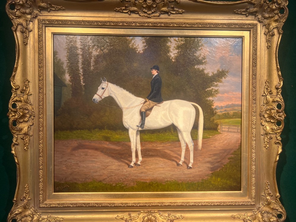 An oil painting on canvas showing a side profile of a rider mounted on a grey horse on a dirt path, enclosed in an ornate gold gilt frame.