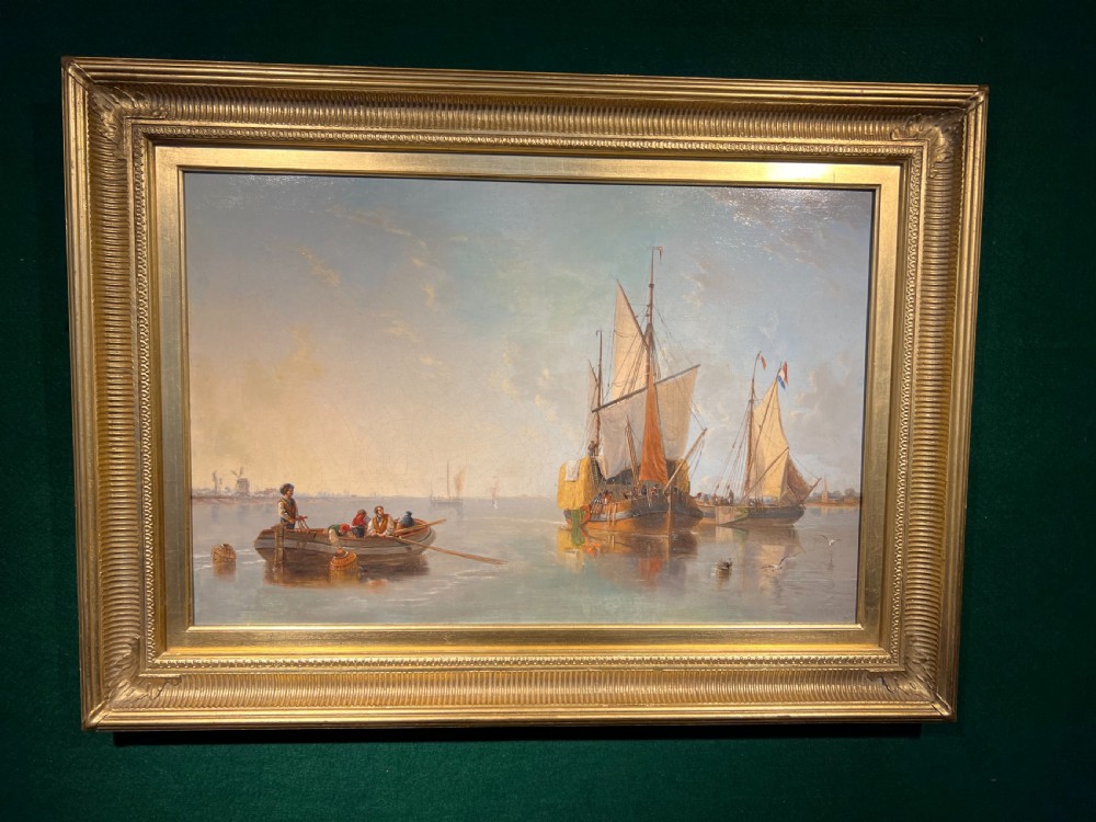 A nineteenth-century framed oil painting depicting sailing vessels and figures in a rowing boat on calm water, set within a fluted gilded frame.