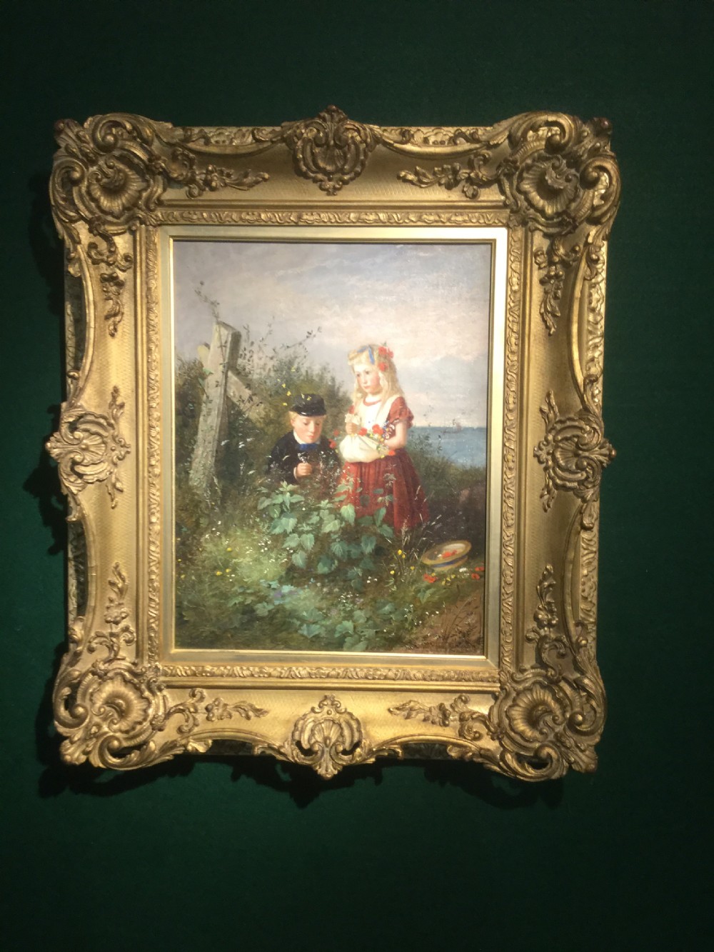 A nineteenth-century oil painting depicting two children outdoors, set within an ornate gilded wood frame.