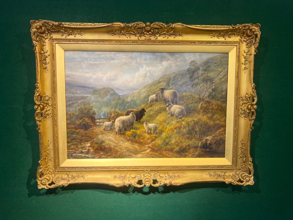 An antique oil painting depicting sheep on a Scottish highland hillside, enclosed in a heavily decorated gold giltwood frame.