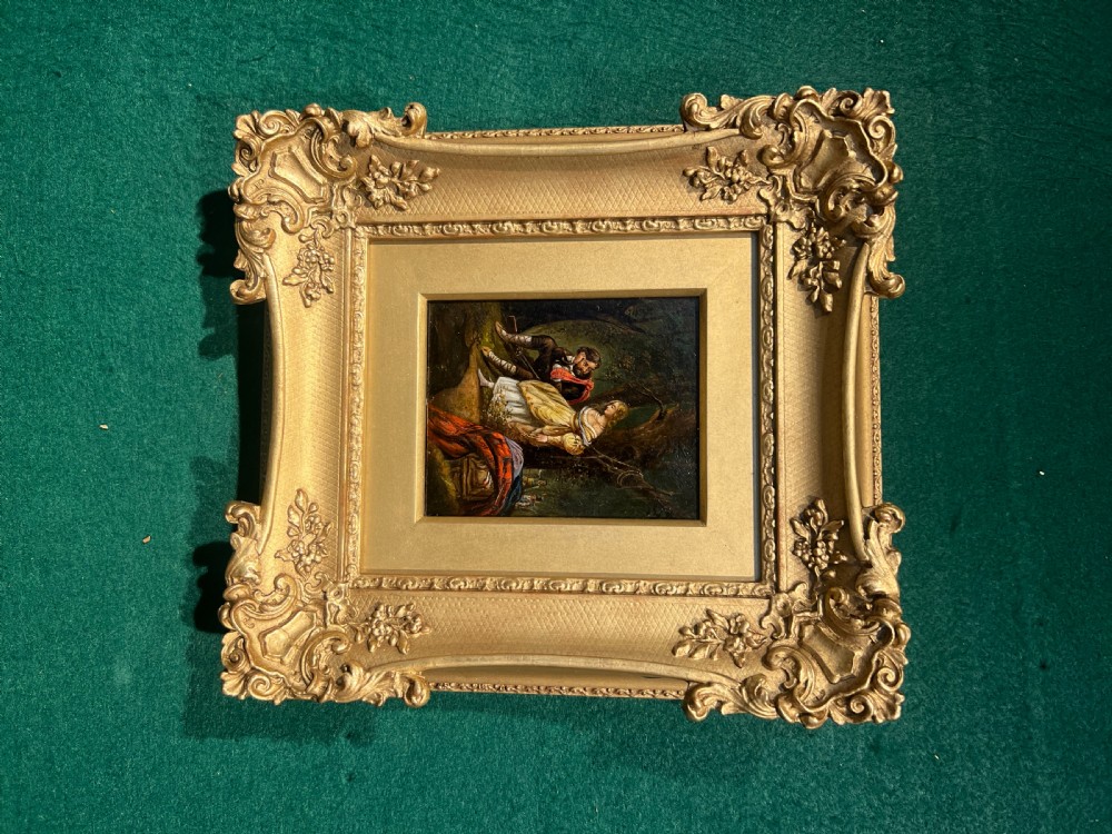 A small nineteenth-century oil painting depicting figures in a woodland landscape, set within an ornate gilded swept frame.